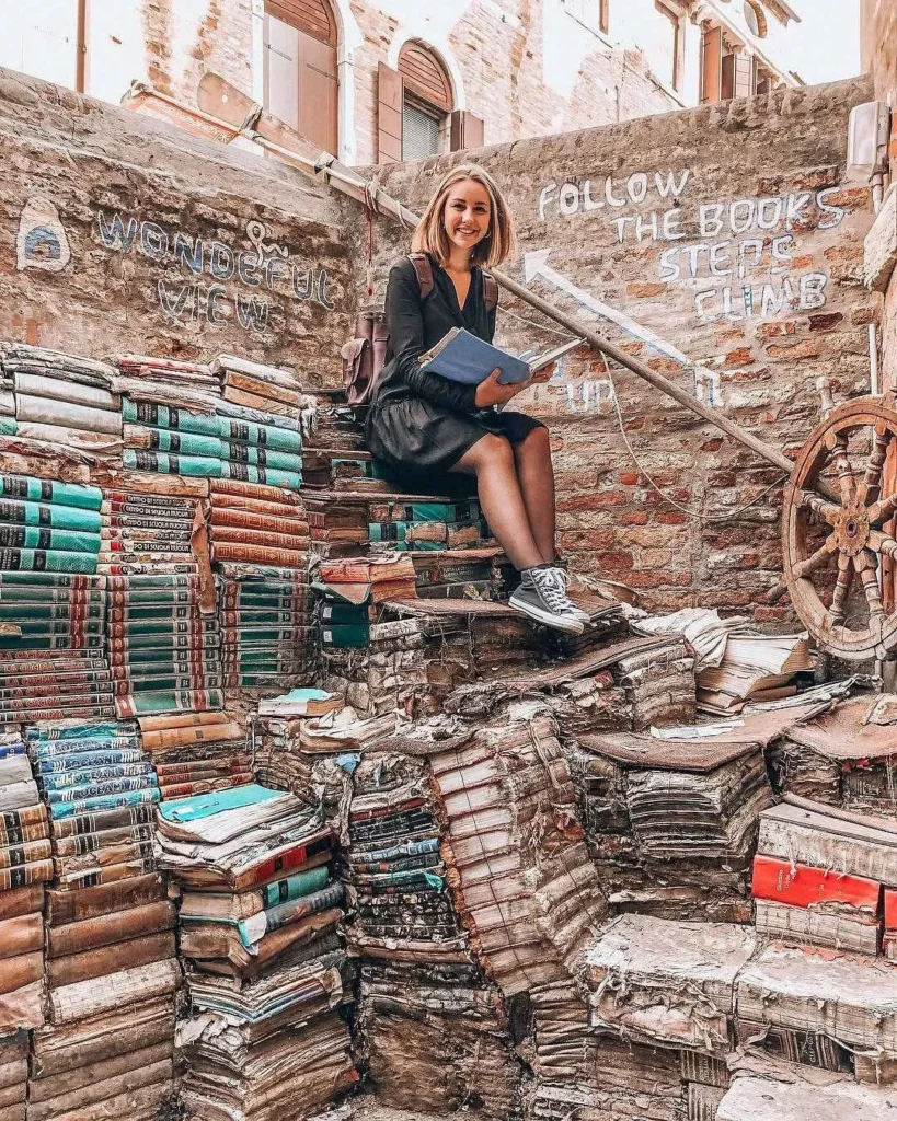 A woman sitting on the famous stairs made of books in Venice
