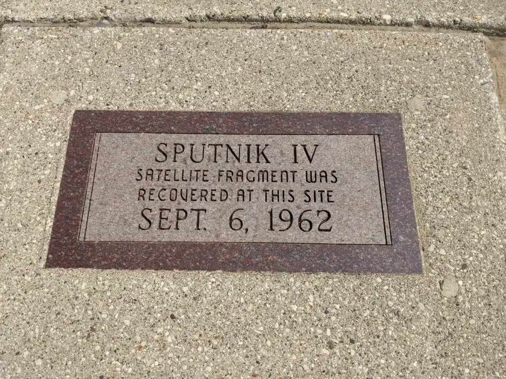 A historic plaque on the pavement, next to the spot in the street where the Sputnik IV piece was found, which is marked by the ring in the road.