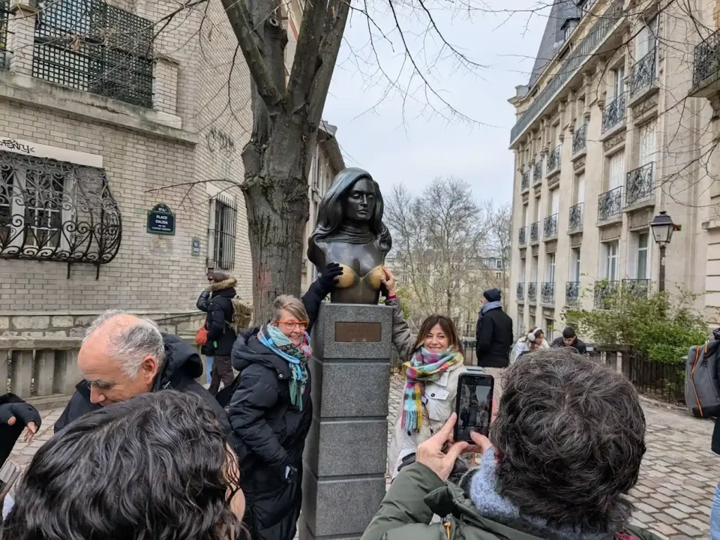 Several tourists rubbing Dalida's bust on the breasts